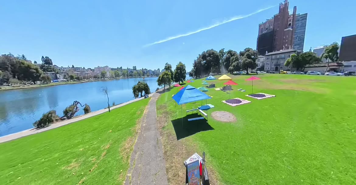 Umbrellas and blankets set up on the lawn at Lake Merritt
